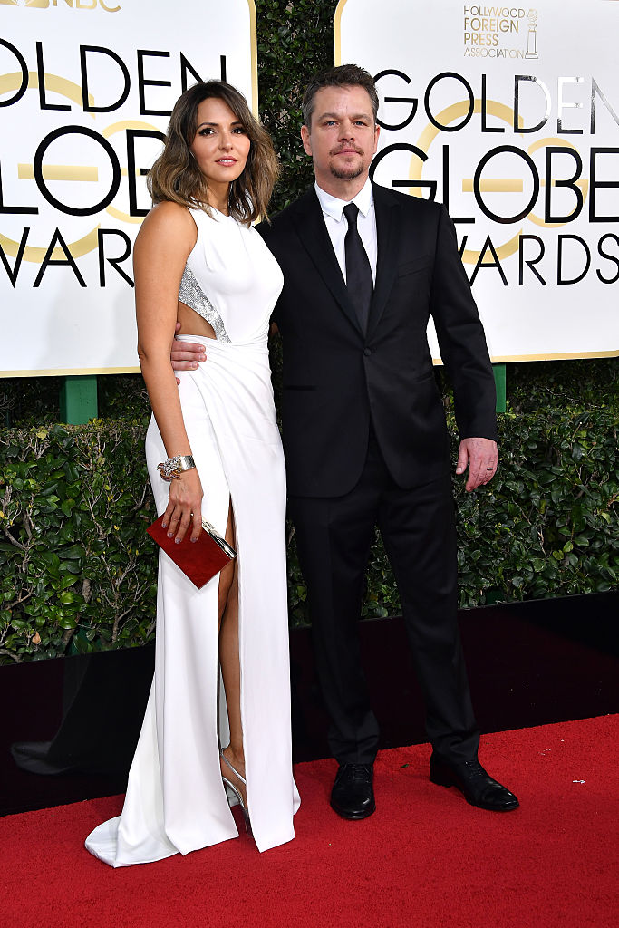 Matt Damon Was Dapper In A Custom-made Black Versace Tuxedo With Bespoke White Shirt And Classic Black Tie.
Luciana Damon Was Breathtaking In A Custom-made, Atelier Versace Gown. She Wore A White Fitted Gown With Cut Out Details, Swarovski Crystal Accents And Leg-baring Slit.